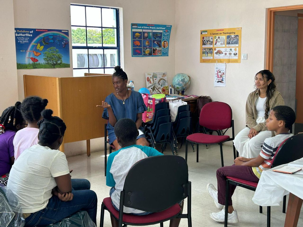 A young woman leads a nutrition session for children seated in a circle at a library in Barbados
